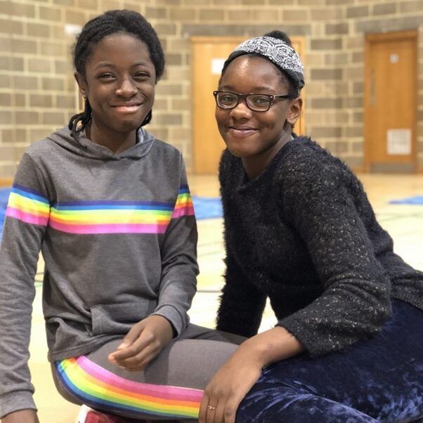 two girls sat together in hall