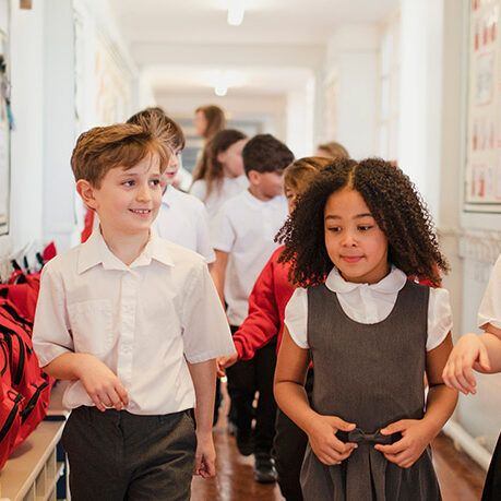 group of children in uniform walking down a hall in school