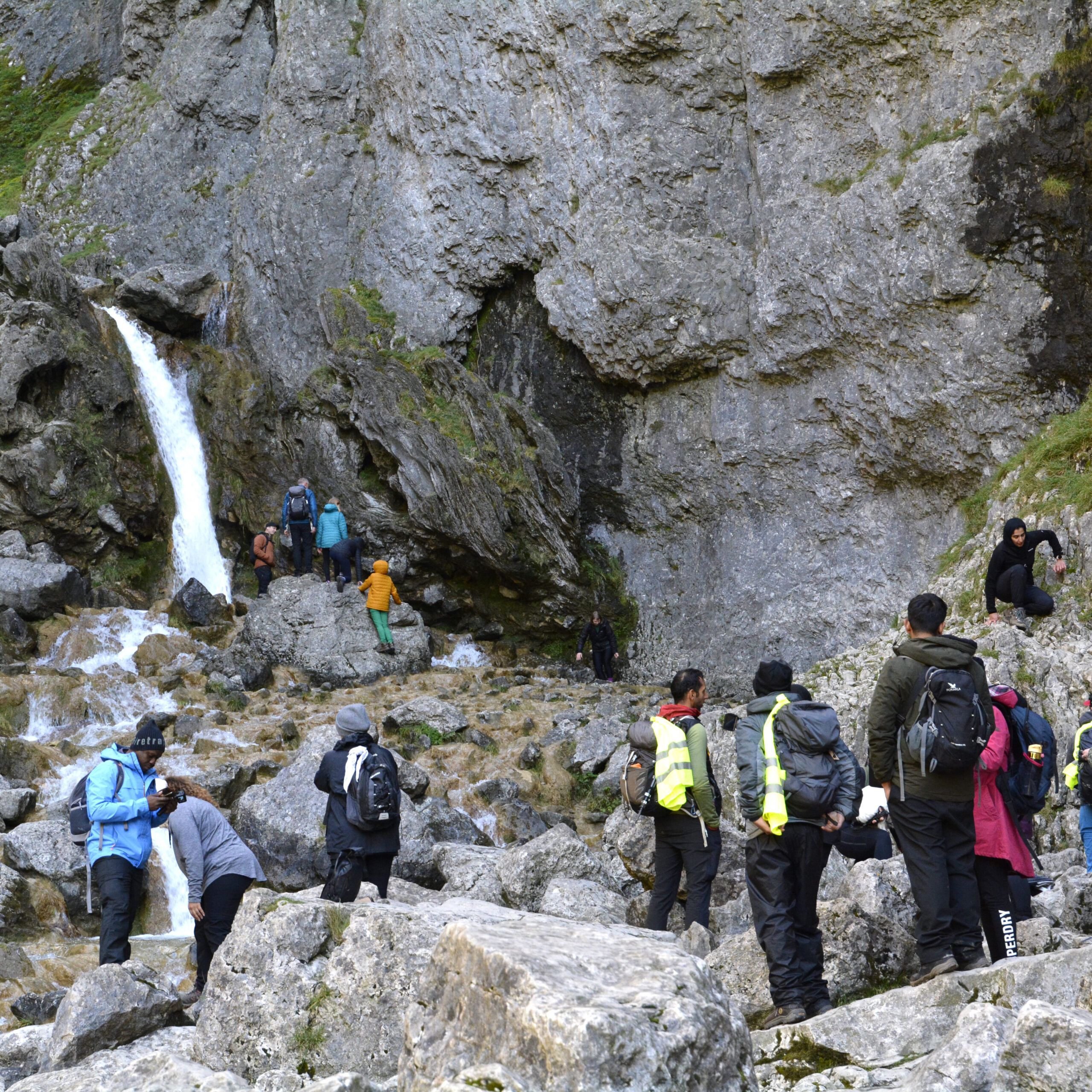 hikers at the bottom of a mountain with waterfall