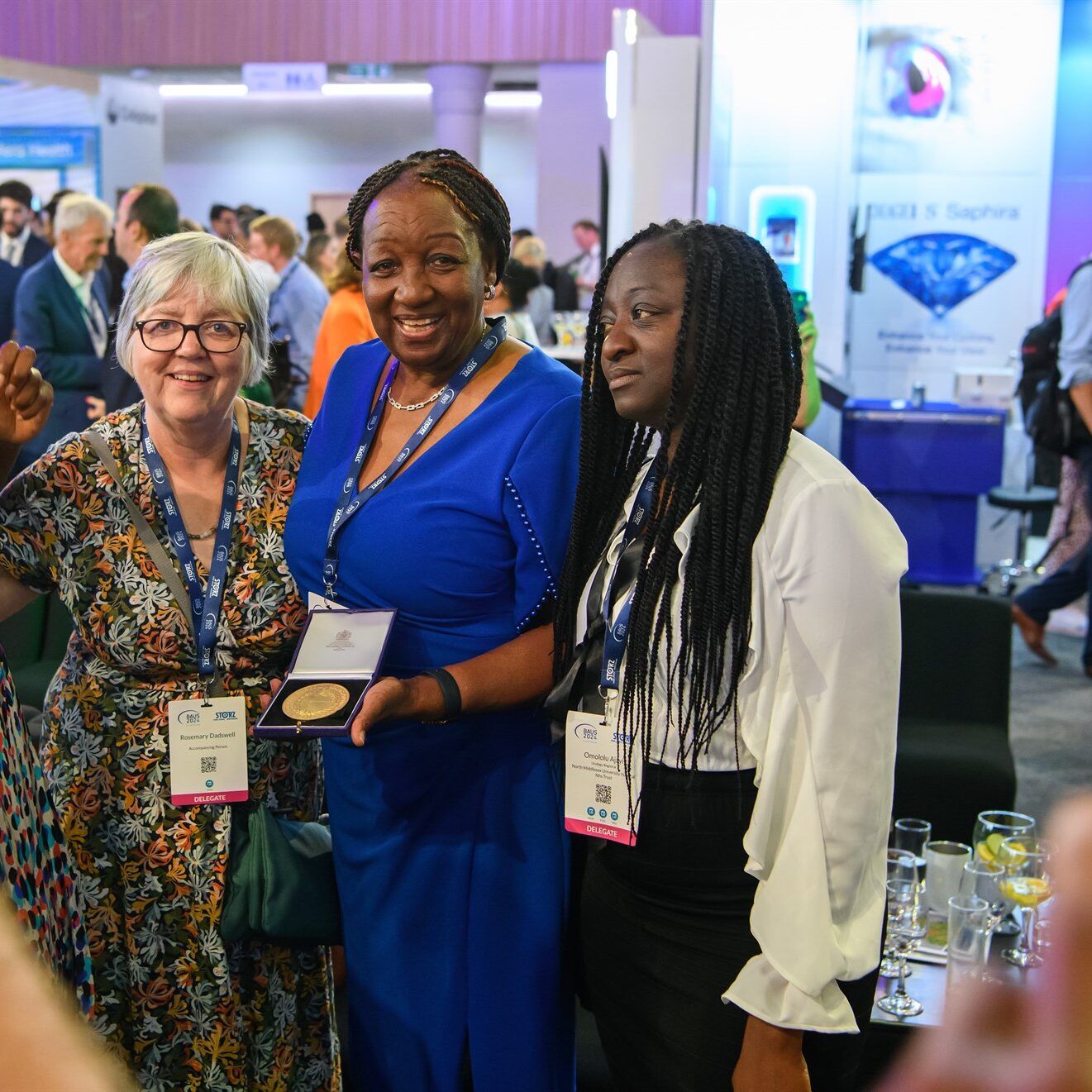 The British Association of Urological Surgeons (BAUS) staff gathered smiling in exhibition setting and holding award