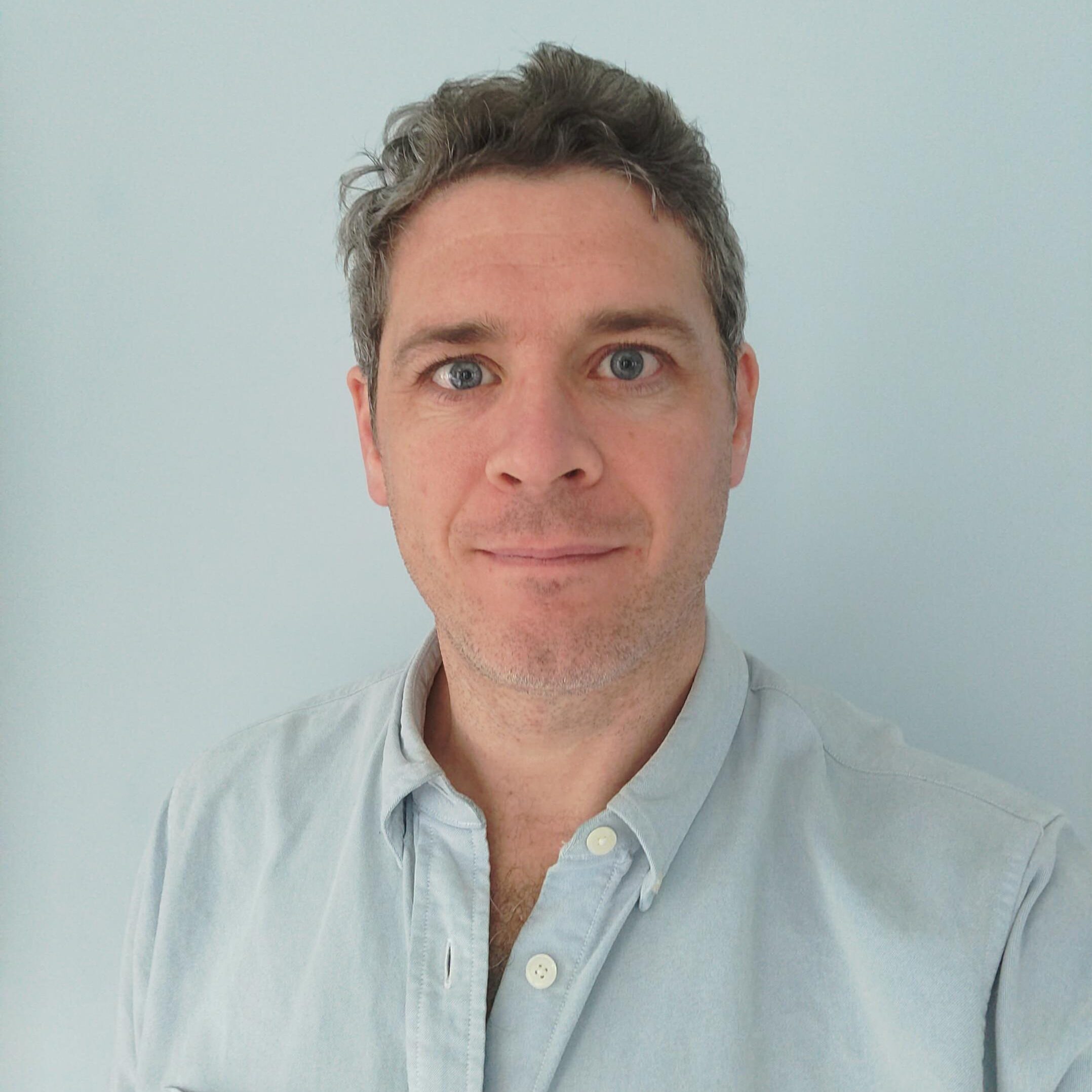 John Sanger charity consultant with blue shirt against blue background