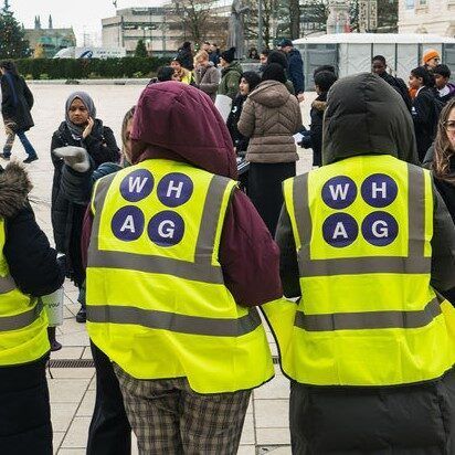 WHAG Head of operations recruitment job Eastside people charity volunteers stood in street in high vis jackets with charity logo on