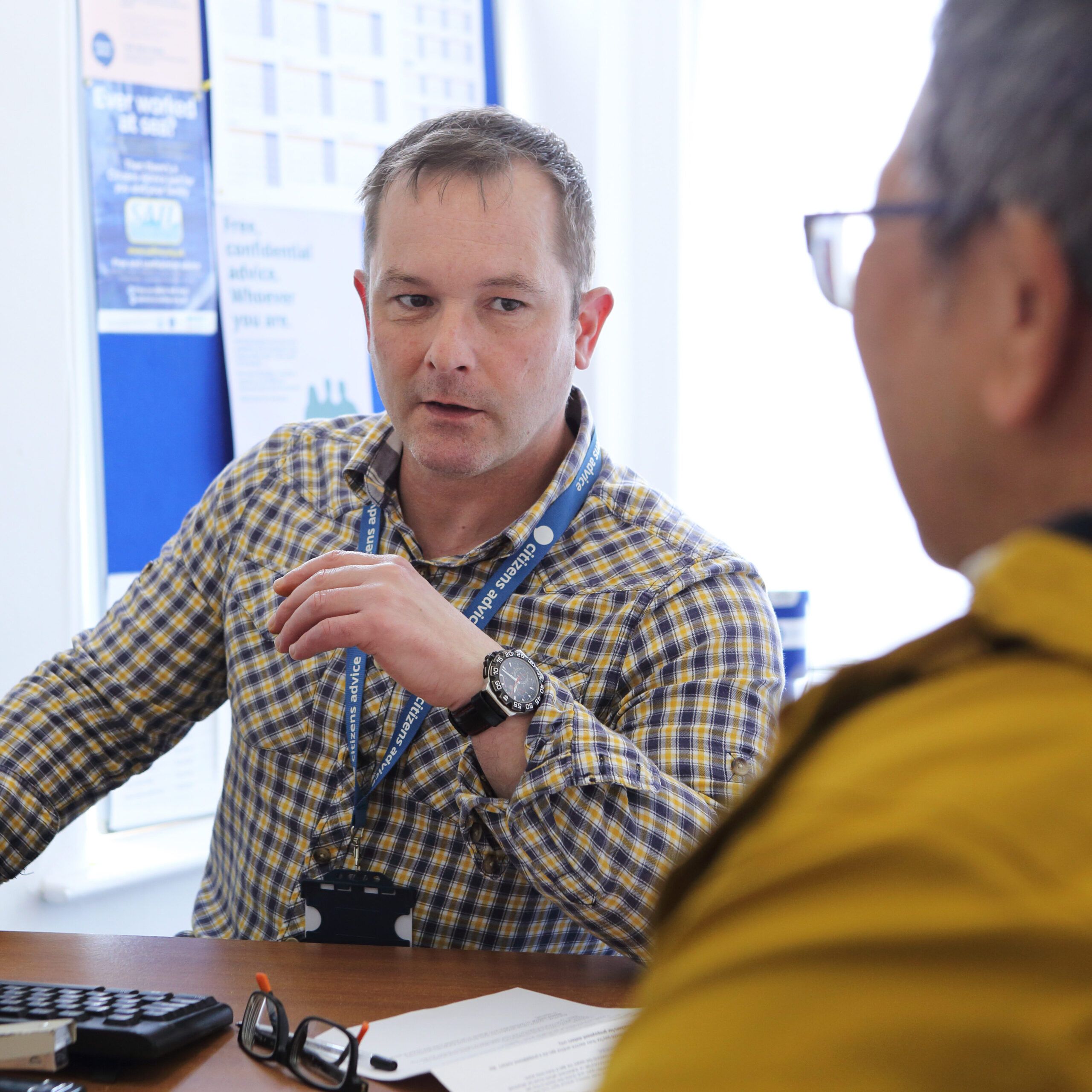 charity volunteer sat at desk talking to a woman