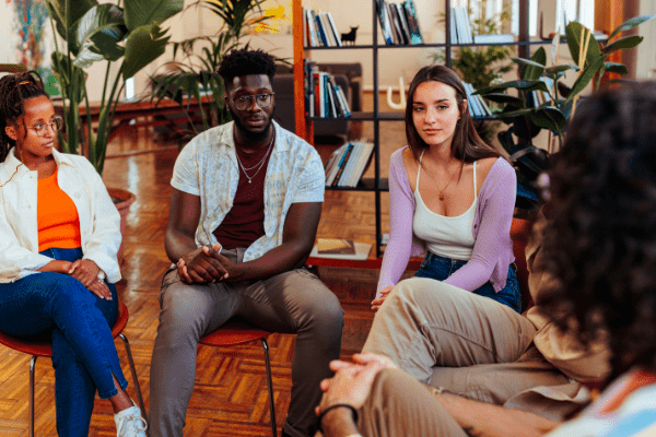 group of young adults sitting on chairs in a circle