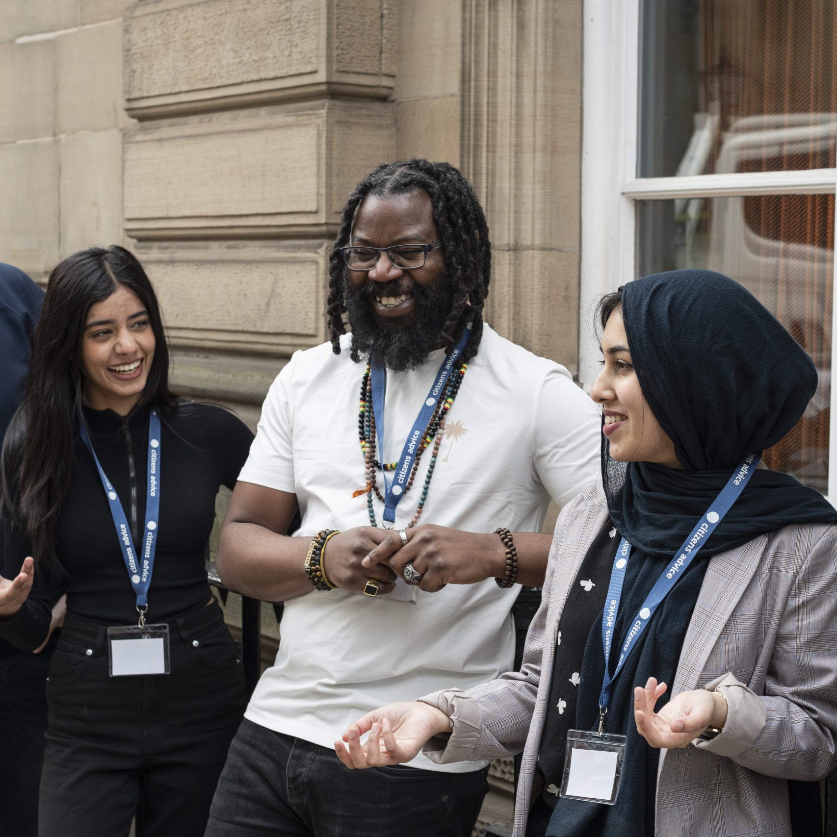 CAWS volunteers - 2 women and a man smiling while talking outside a building.