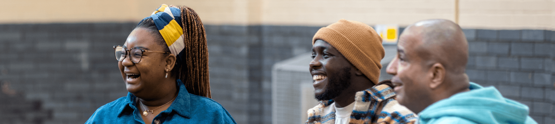 3 black adults smiling seated on chairs. Blog Social Value to measure Impact Alastair Tallon Website Banner (1920 x 430)