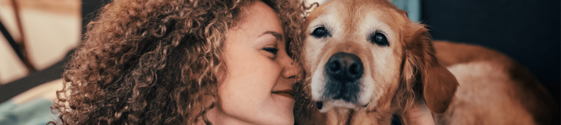 Woman looking happy nuzzling up to a dog