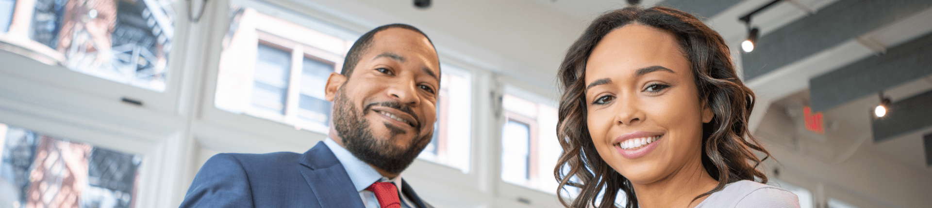 A banner slide with a photo of a black man and woman smiling accompanying the blog about charity partnerships by Dolyanna Mordochai