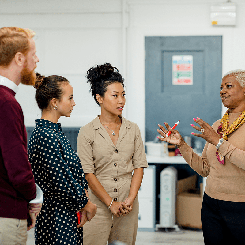 AdviceUK-4-people-having-a-discussion-aspect-ratio-1-1 AdviceUK 4 people (3 female and 1 male) having a discussion standing up. 1 is holding a pen.