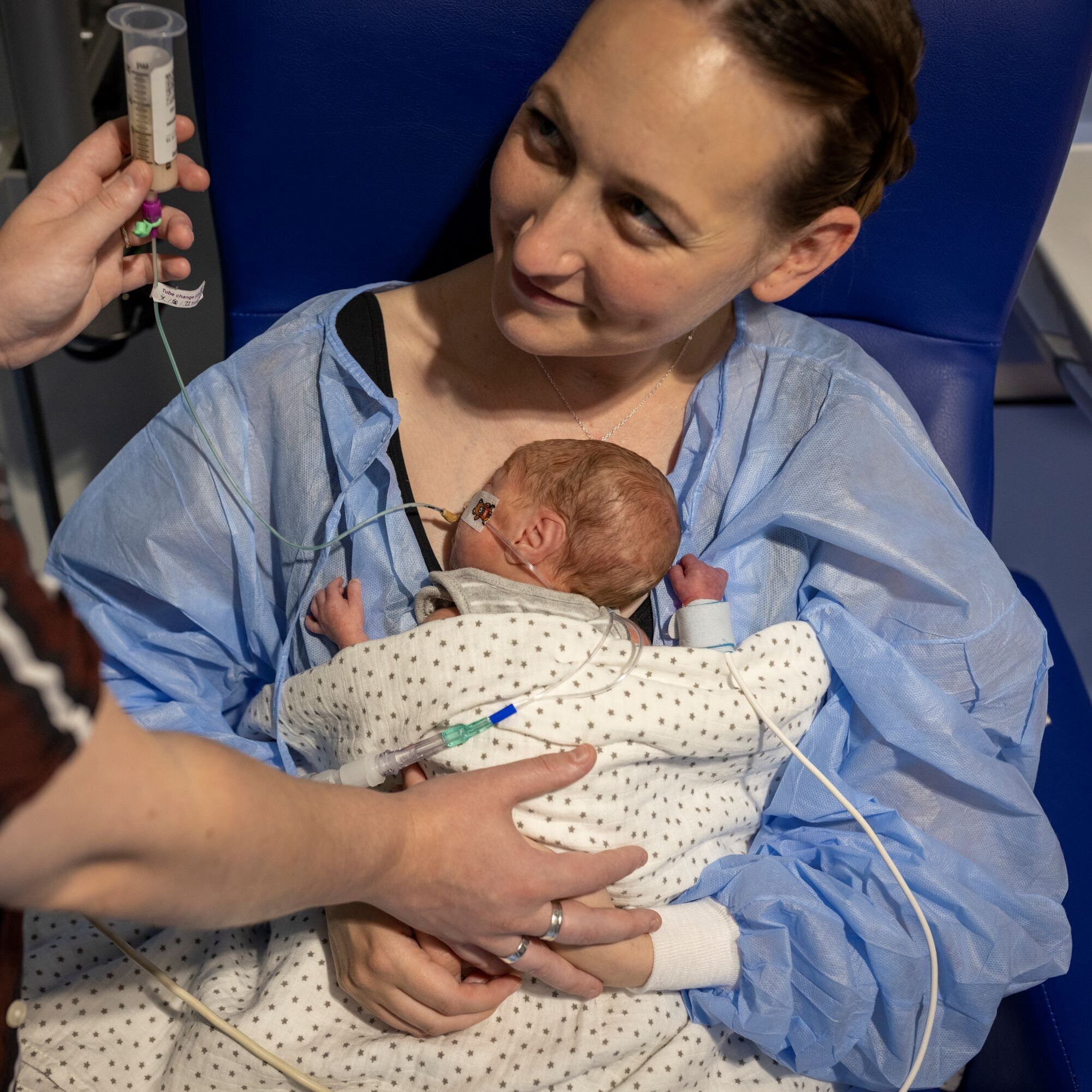 Bliss mother holding a very small baby linked up a a tube of liquid