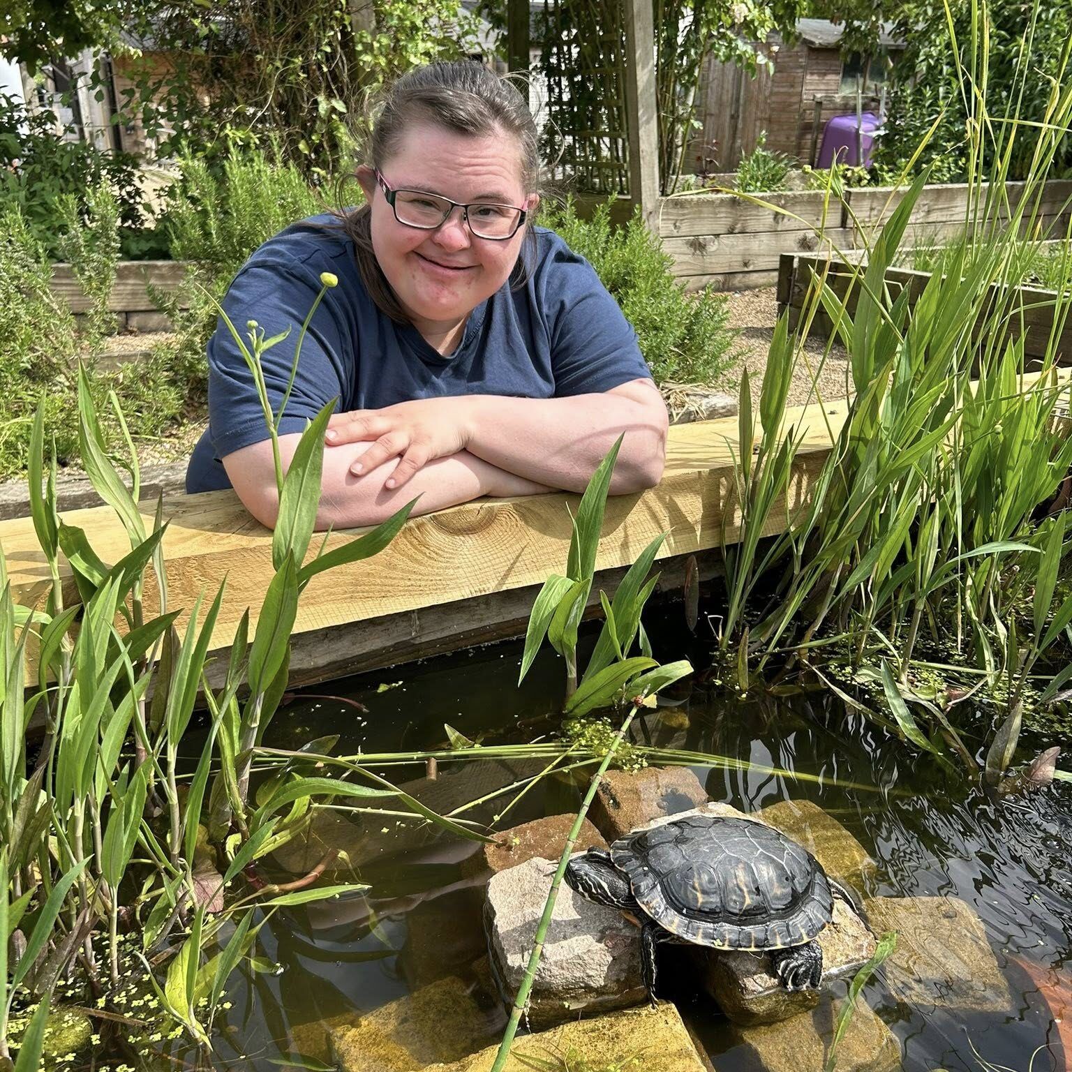 Millennium Farm Trust man wearing glasses looking at a tortoise