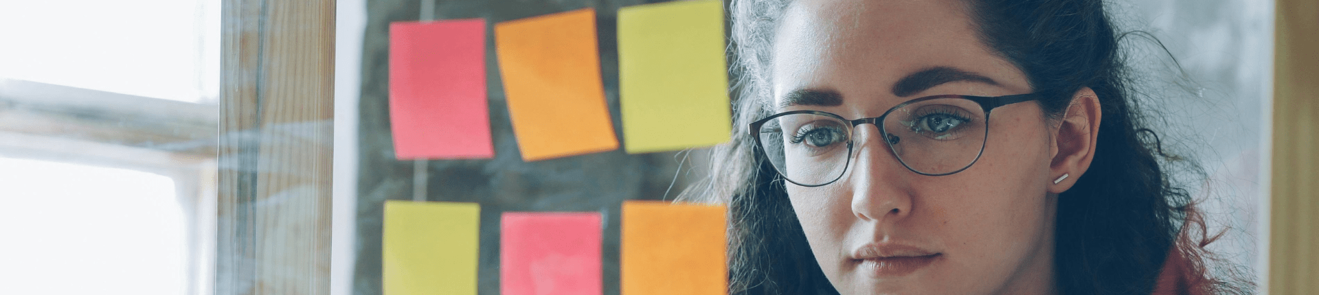 Image of a girl wearing glasses and sticking up post-it notes