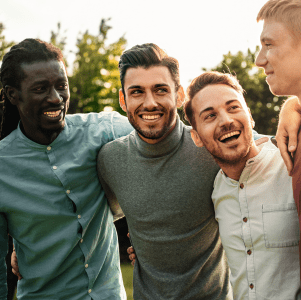 4 men arms interlocked. 1 is black and 2 have beards.