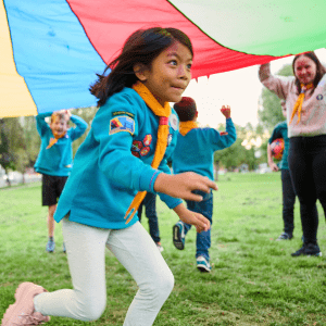 Greater Manchester East Scouts children outdoor having fun with a large parachute being lifted up by a adult scout leader.