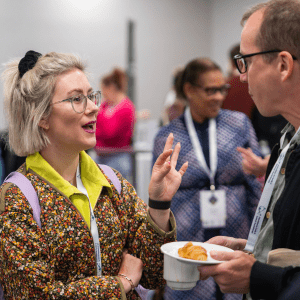 Association for Family and Systemic Psychotherapy members - man and woman talking to each other at an event.